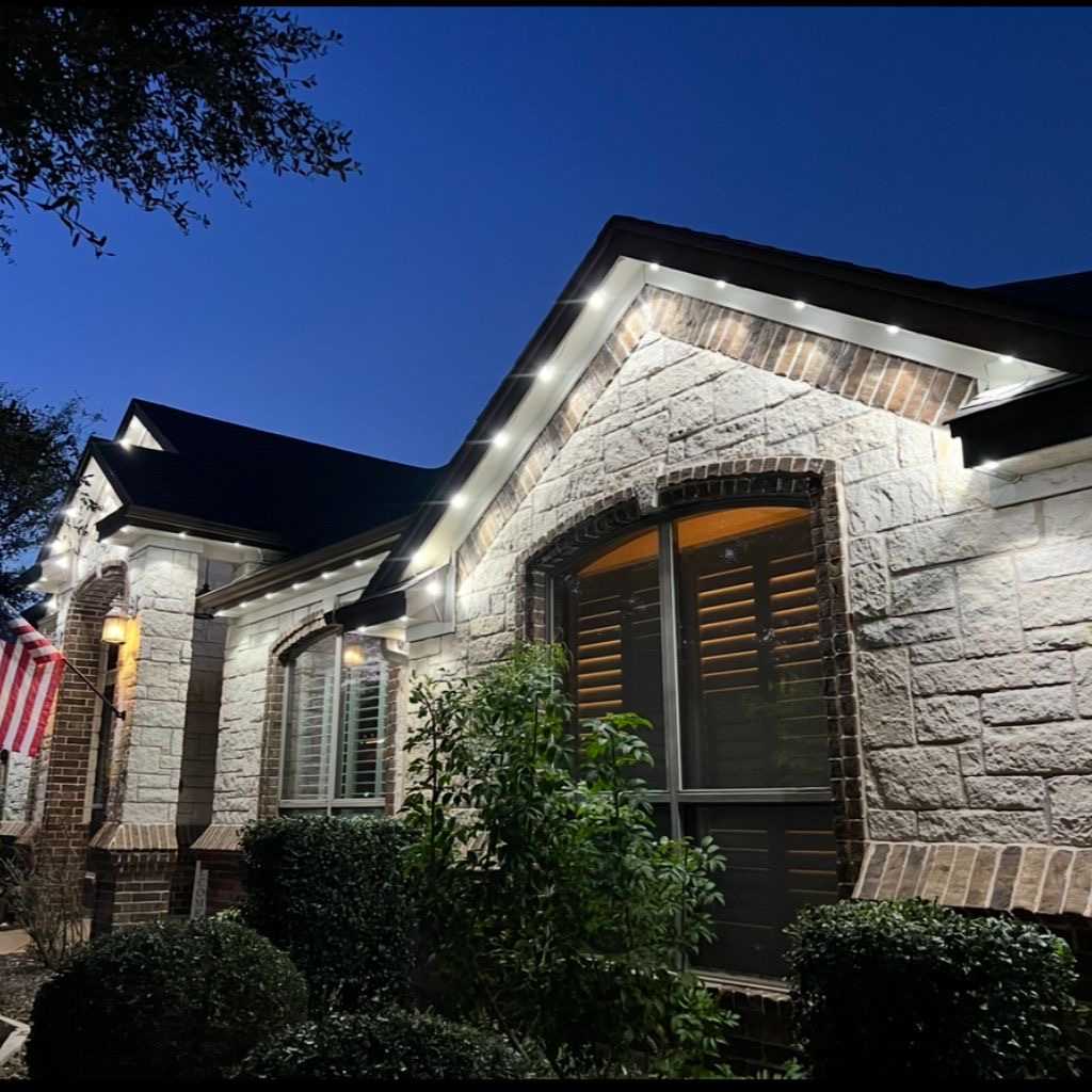 Stone home with crisp white permanent LED accent lighting at dusk