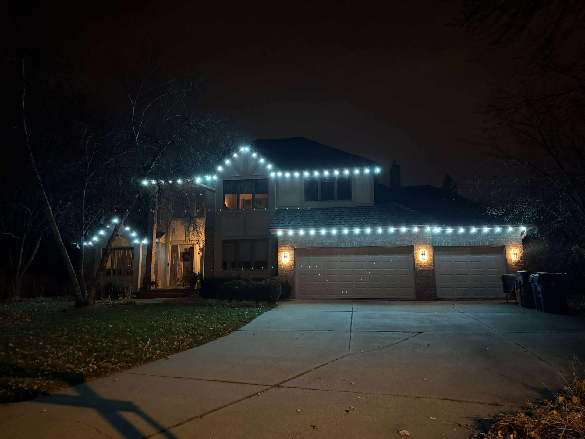 Two-story home outlined in cool white permanent LED lighting